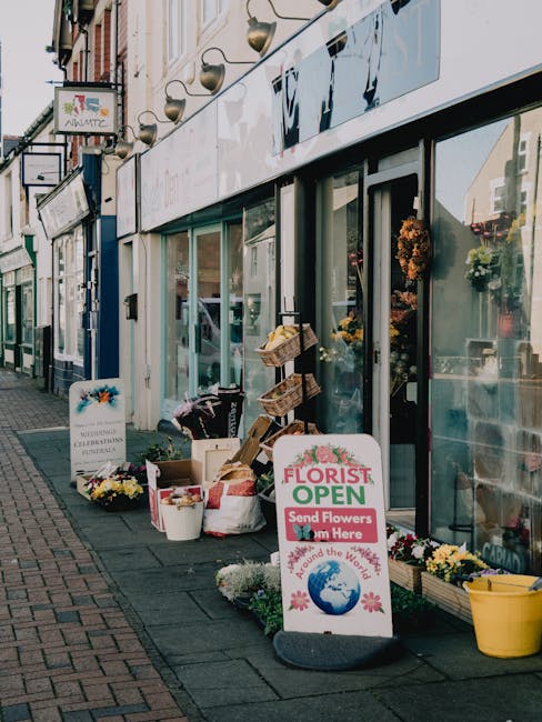 The image depicts the storefront of a florist shop, identified by a prominent 'Florist Open' signboard placed on the pavement outside, advertising flower delivery services for Dartford station and Hig