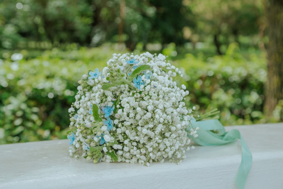 A floral bouquet composed primarily of small white baby's breath (Gypsophila) with delicate light blue flowers subtly integrated throughout. The bouquet is arranged in a rounded, compact style and is 